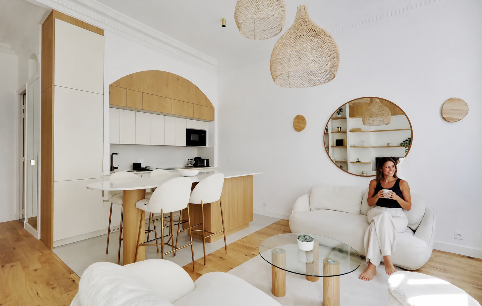 Salon et cuisine après rénovation d'un appartement parisien, une femme est assise sur le canapé.