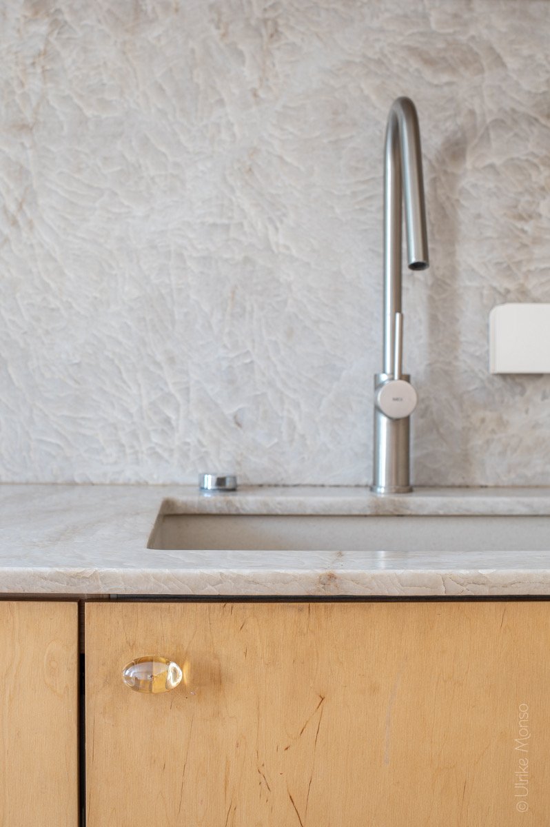 Évier moderne en marbre avec robinet en acier inoxydable et tiroir en bois clair, créant une ambiance élégante.