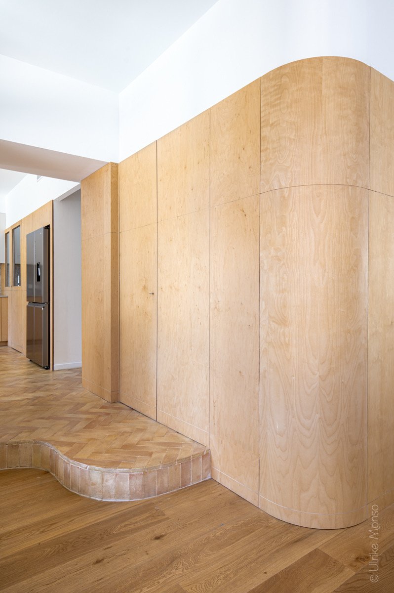 Intérieur moderne avec des murs en bois clair et un sol en parquet, mettant en valeur des lignes épurées et des courbes douces.