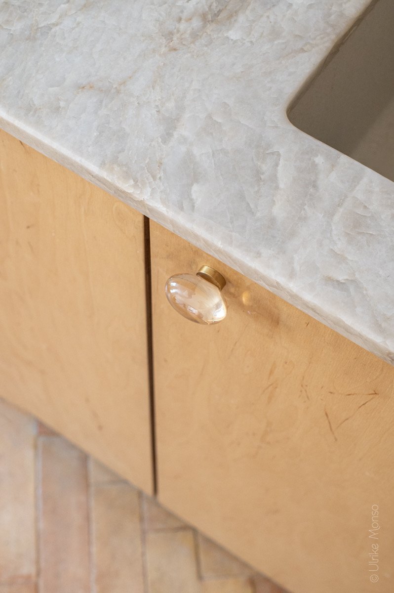 Lavabo en marbre avec un tiroir en bois et une poignée en verre, ajoutant une touche élégante à l'espace.