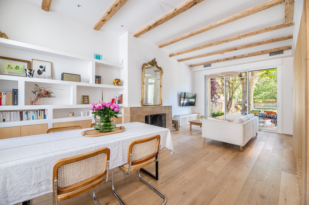 Intérieur lumineux et moderne avec une table à manger, des fleurs, un salon confortable et une vue sur le jardin.